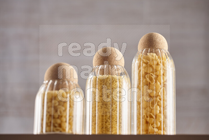 Raw pasta in glass jars on beige background