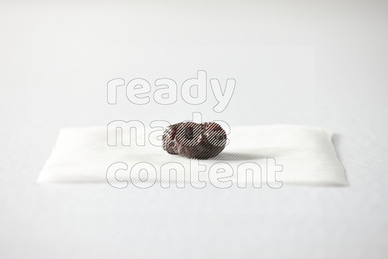 A dried plum on a piece of paper on a white background in different angles