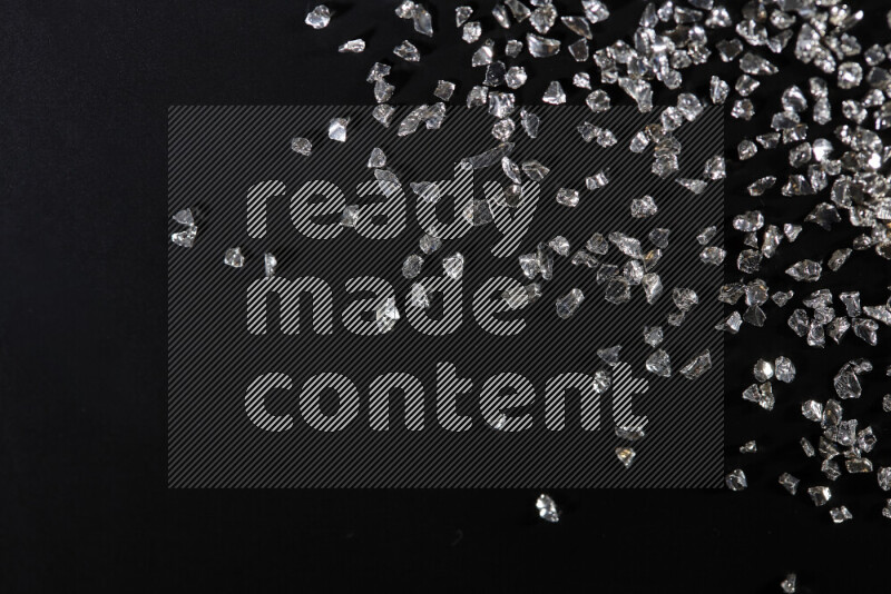 Silver shimmering fragments of glass scattered on a black background