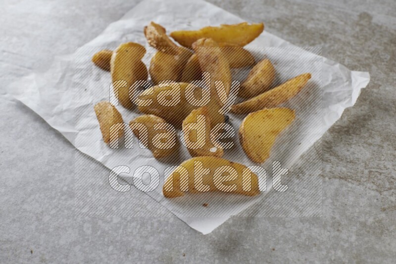wedges potato on parchment paper on grey textured counter top