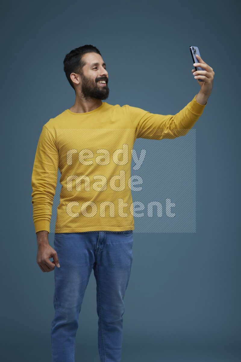 Man Taking a Selfie  in a blue background wearing a yellow shirt