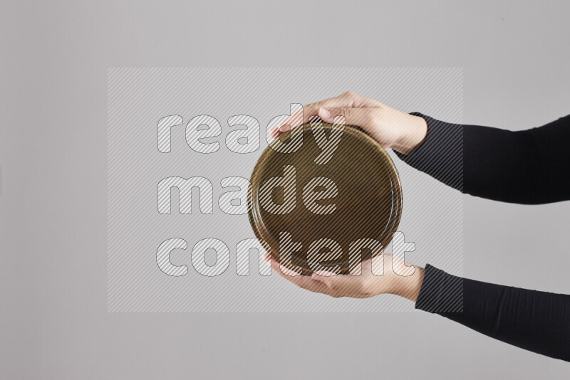 A woman in black abaya holding different pottery essentials in different positions