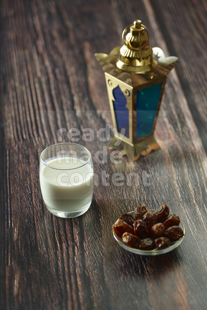 A golden lantern with different drinks, dates, nuts, prayer beads and quran on brown wooden background