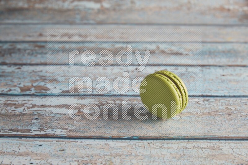 45º Shot of Green Pistachio macaron on light blue wooden background