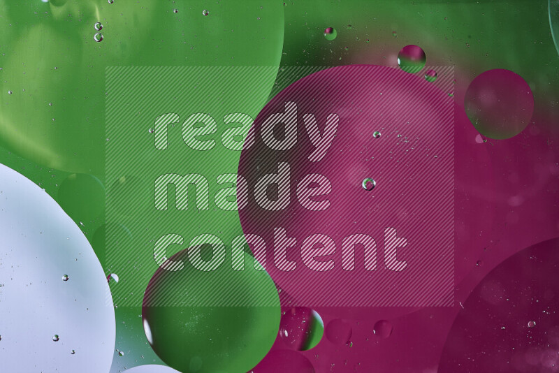 لقطات مقربة لفقاعات من الزيت على سطح الماء باللون الأخضر والوردي