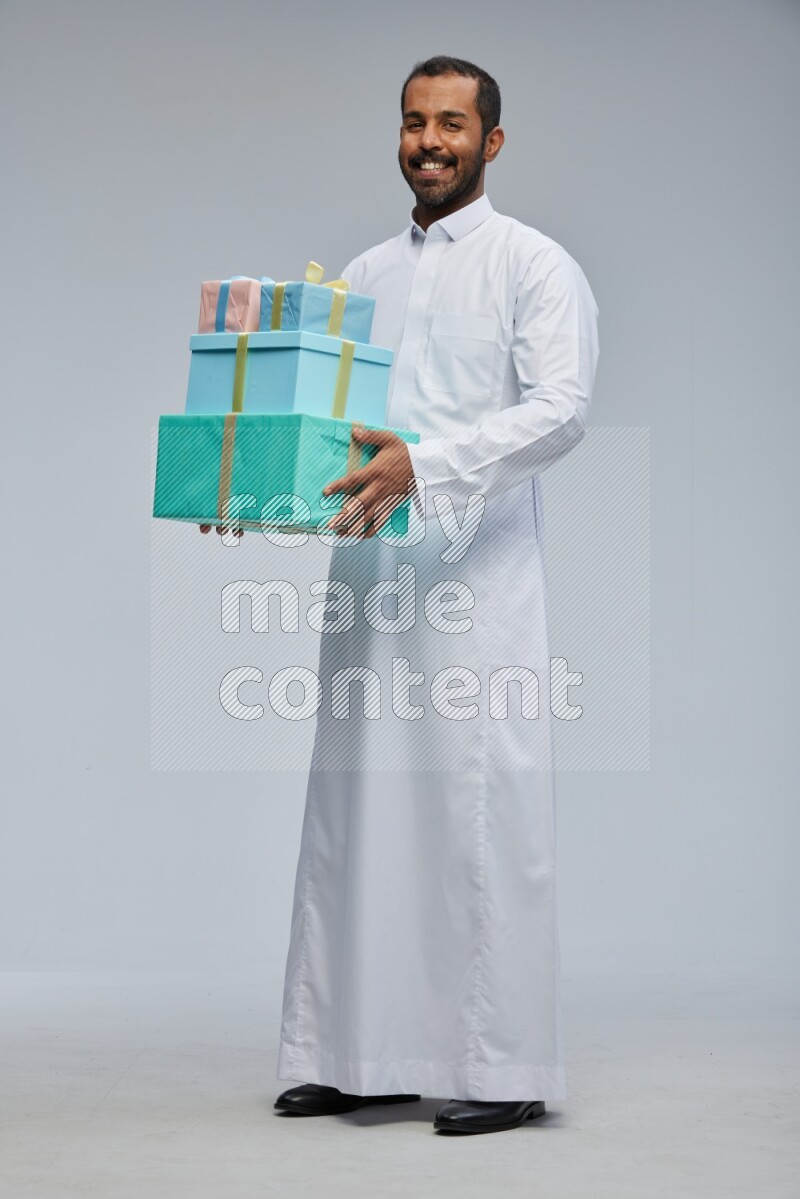 Saudi man Wearing thob standing holding gift box on Gray background