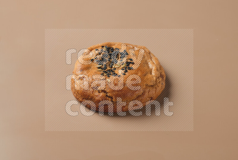 a whole Hasawi cookie with grains on a brown background