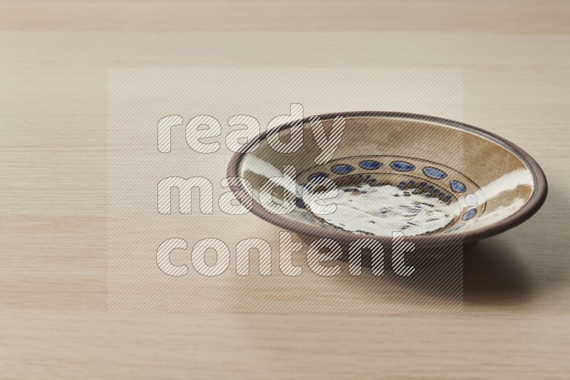 A decorative pottery plate on light wooden background