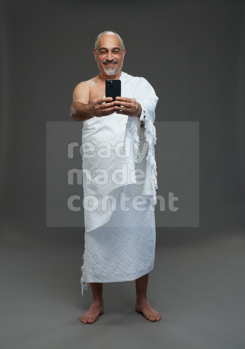 A man wearing Ehram Standing taking selfie on gray background