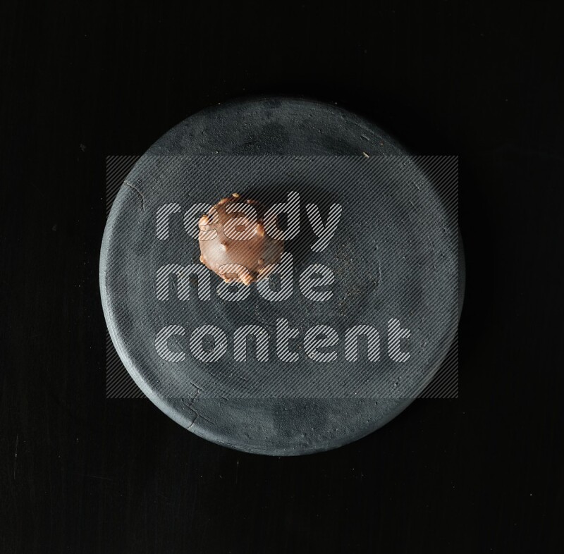 Assorted desserts in a black pottery plate on black background