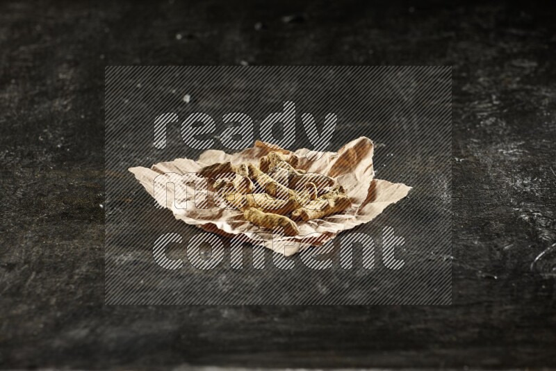 أصابع الكركم المجففة في قطعة من الورق على خلفية سوداء