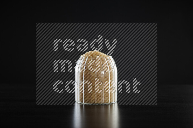 Basmati golden rice in a glass jar on black background