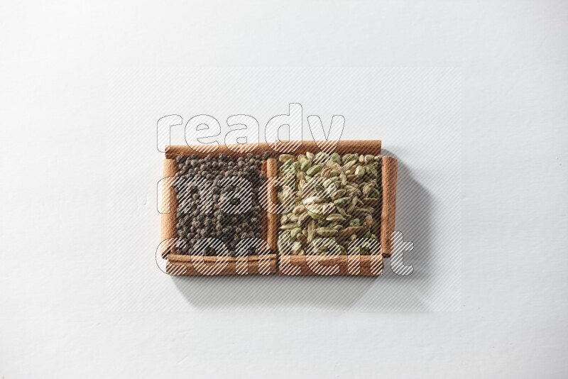 2 squares of cinnamon sticks full of cardamom and black pepper on white flooring