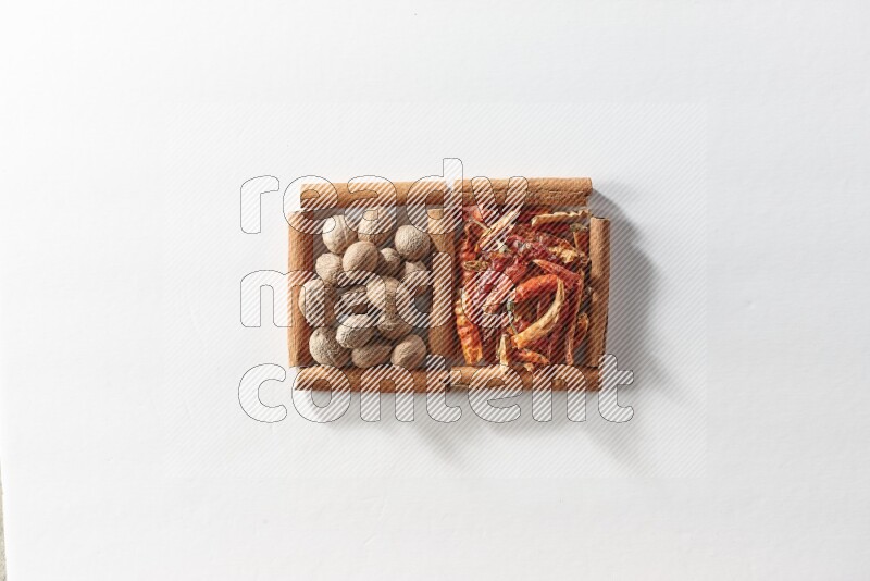 2 squares of cinnamon sticks full of dried red chilis and nutmegs on white flooring