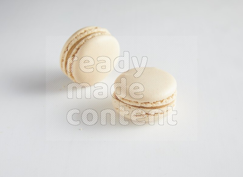 45º Shot of two White Caramel fleur de sel macarons on white background