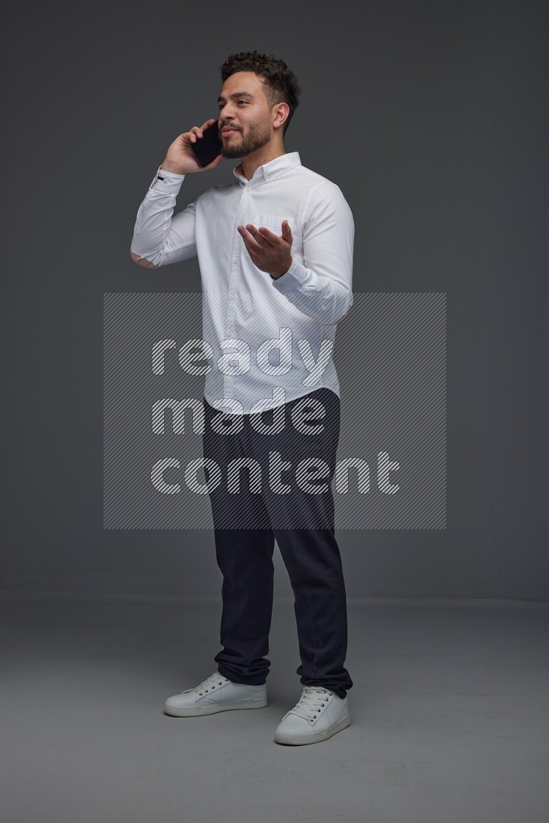 A man wearing smart casual talking in the phone eye level on a gray background