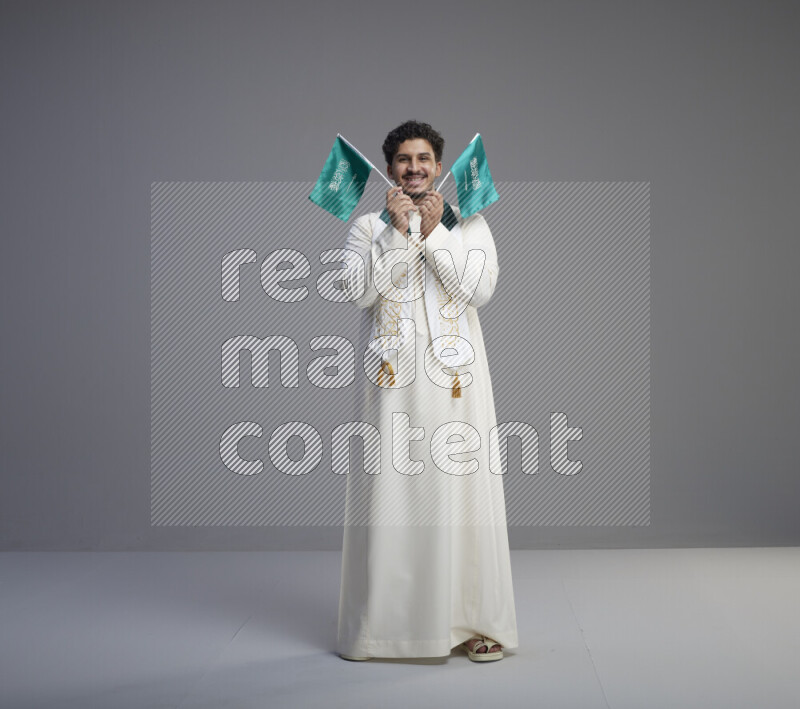 رجل سعودي يرتدي ثوب ابيض ويحمل علم السعودية