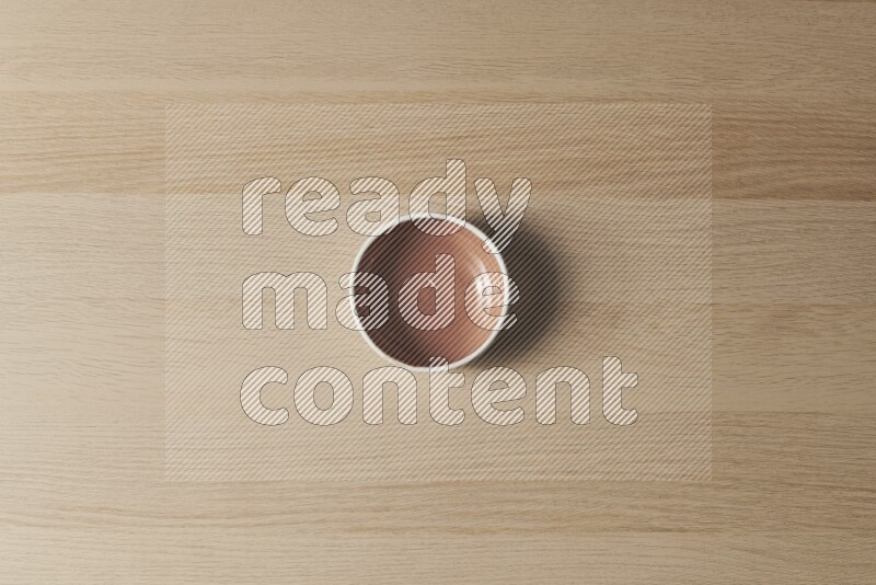A brown pottery bowl on light wooden background