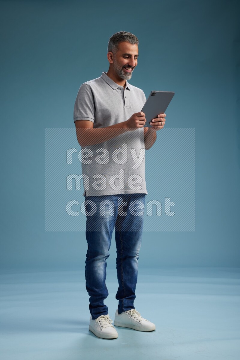 Man Standing working on tablet on blue background