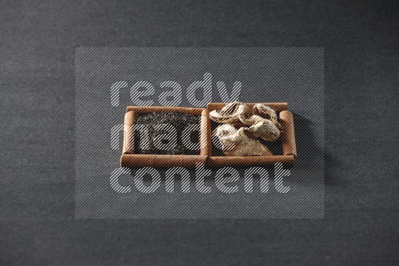 2 squares of cinnamon sticks full of dried ginger and black tea on black flooring