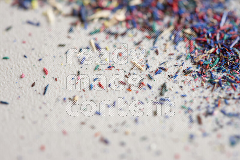 This image showcases a vibrant multicolored pencil shavings scattered on grey background