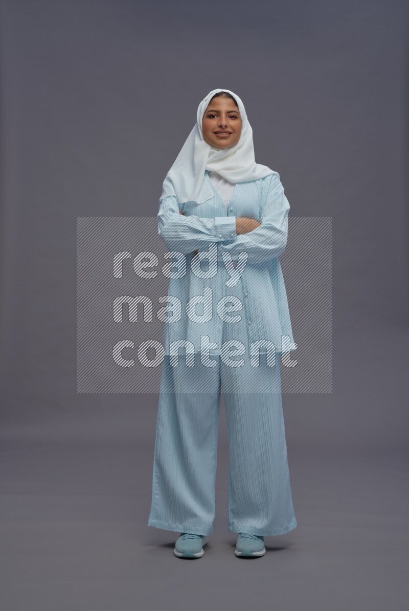 Saudi woman wearing hijab clothes standing with crossed arms on gray background