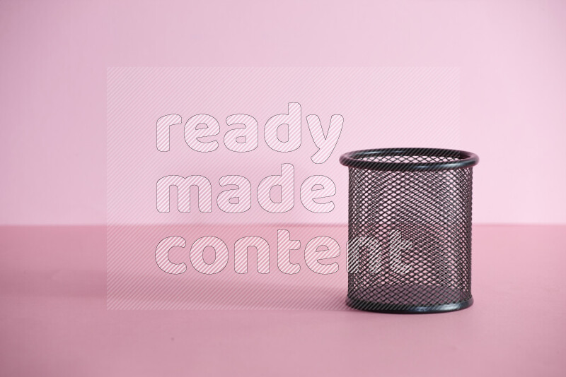 Pens, pencils and other different school supplies in a metal pen holder on rose background