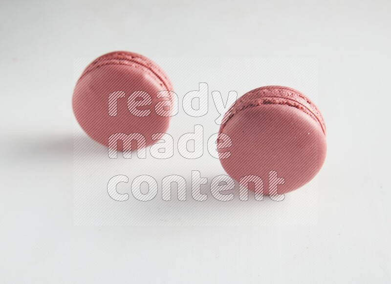 45º Shot of two Pink Raspberry macarons on white background