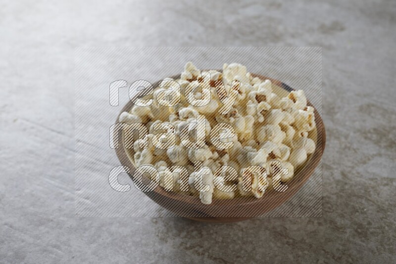 popcorn in wooden bowl on a grey textured countertop