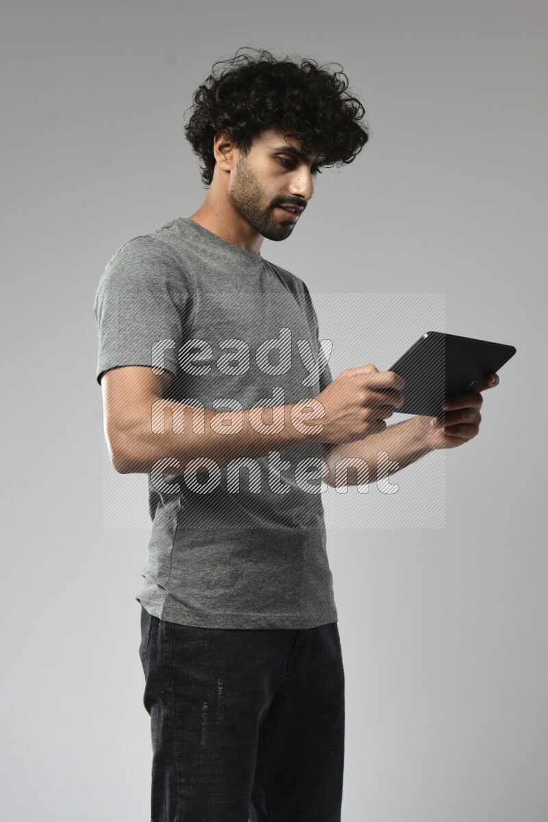 A man wearing casual standing and gaming on a tablet on white background