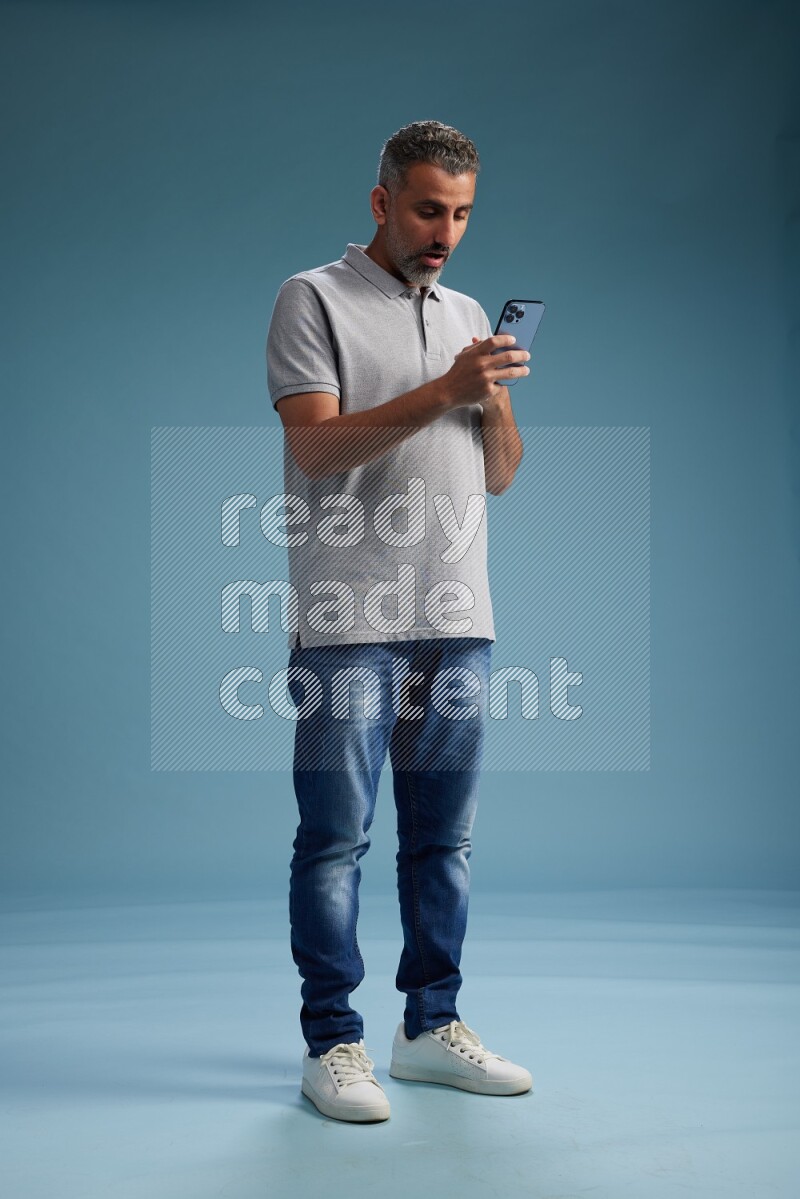 Man Standing texting on phone on blue background