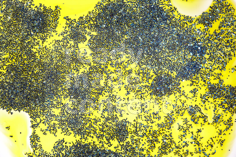 A close-up of sparkling blue glitter scattered on swirling yellow background