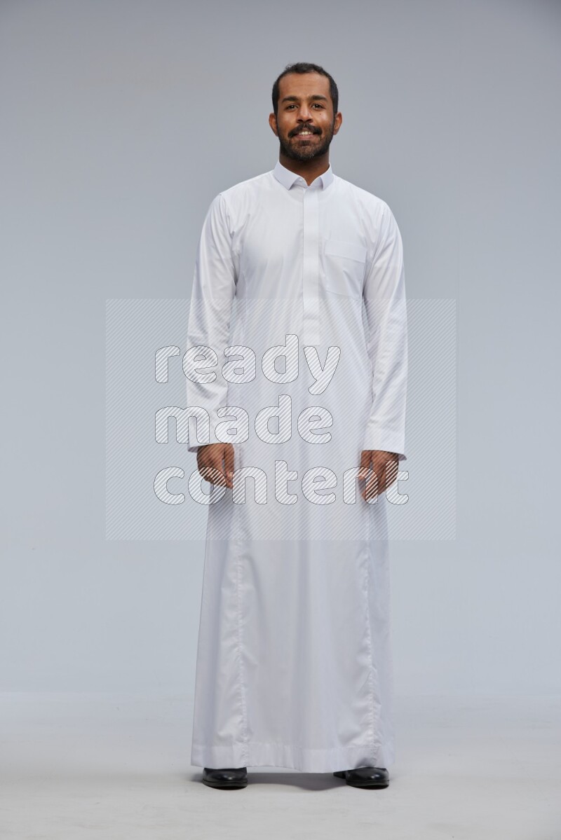 Saudi man Wearing Thob standing interacting with the camera on Gray background