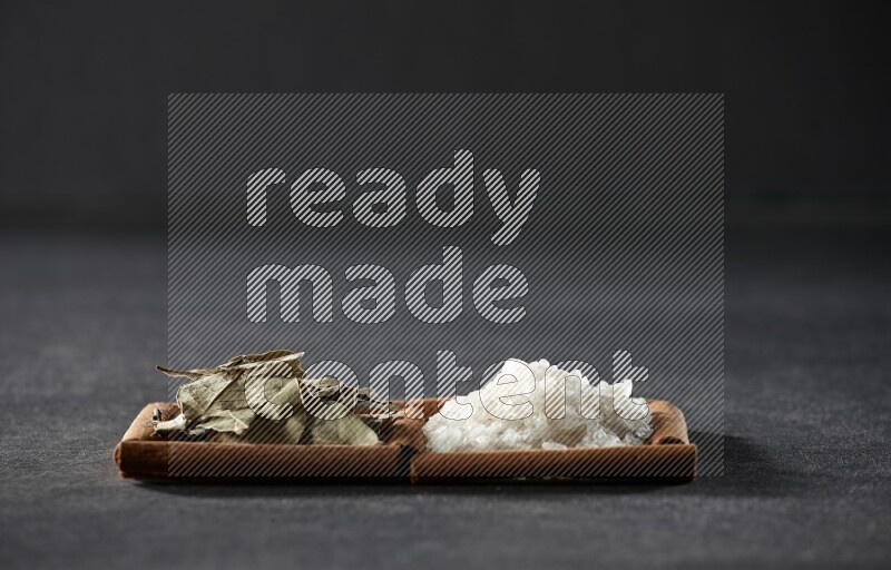 2 squares of cinnamon sticks full of salt and bay laurel on black flooring