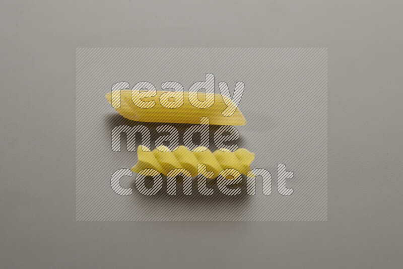 Penne pasta with other types of pasta on grey background