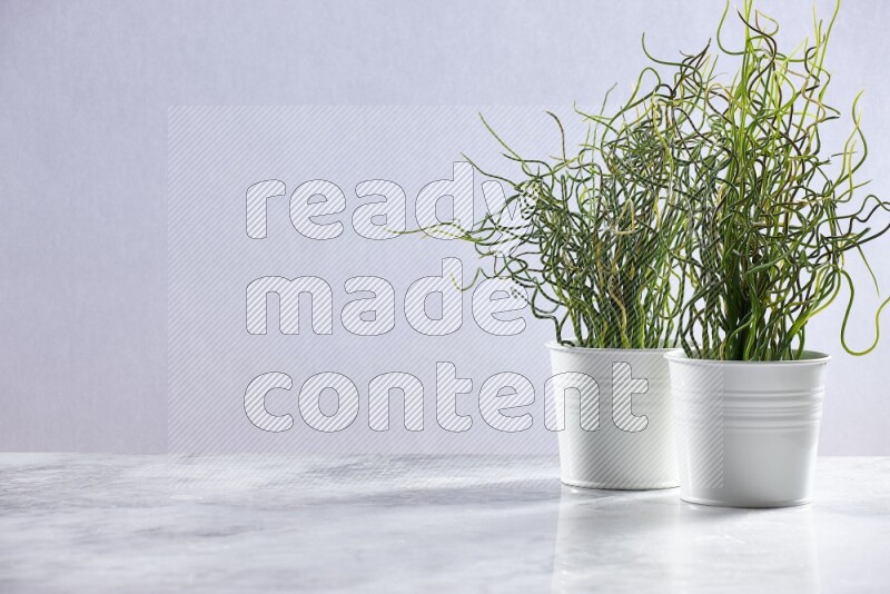 Two green artificial plants in white pot on grey marble background