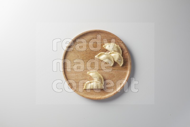 Five Sambosas on a wooden round plate on a white background