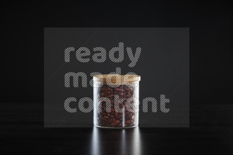 Red kidney beans in a glass jar on black background