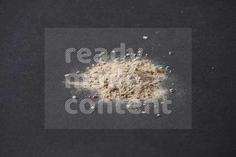 A small pile of garlic powder on a black background