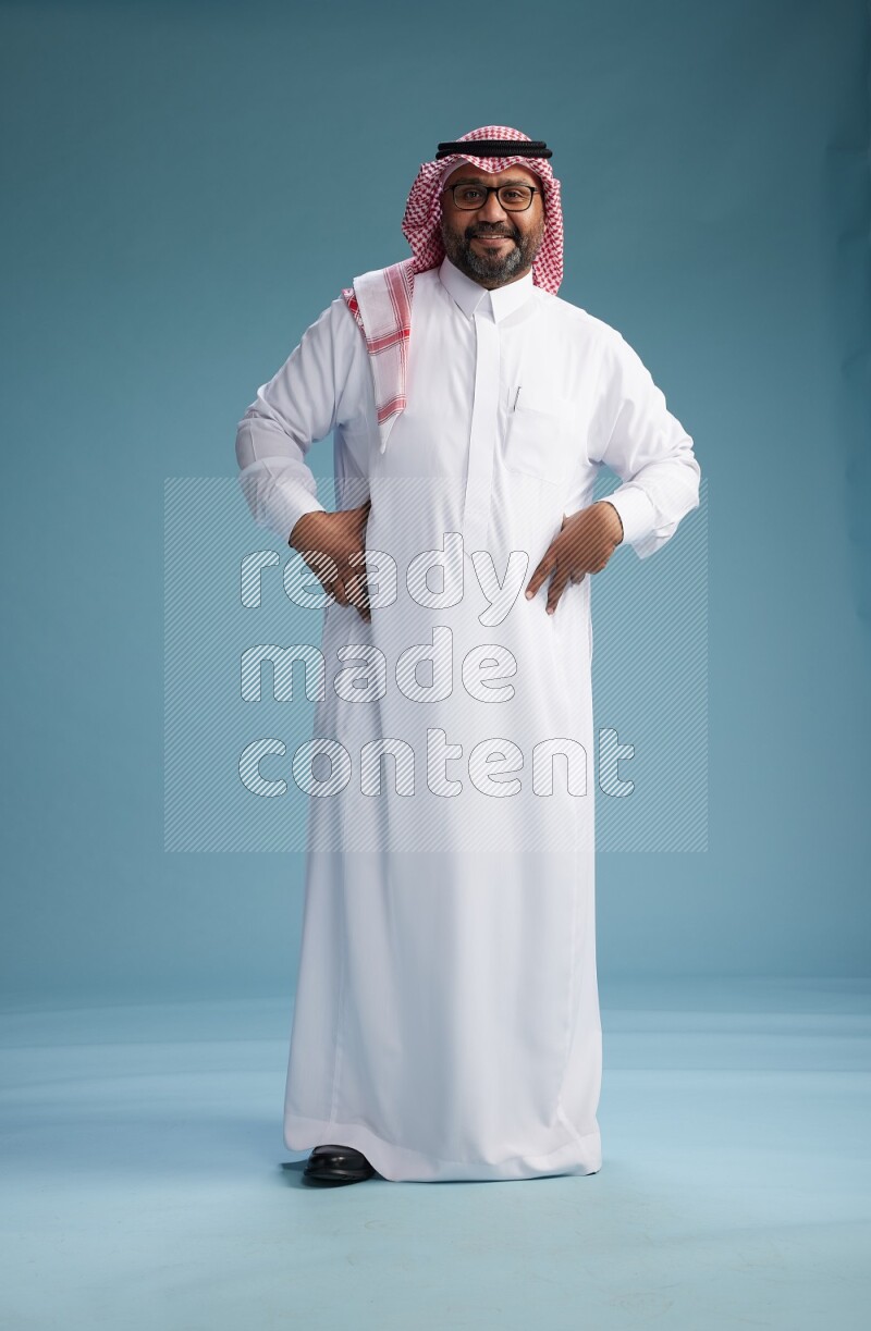 Saudi Man with shimag Standing Interacting with the camera on blue background