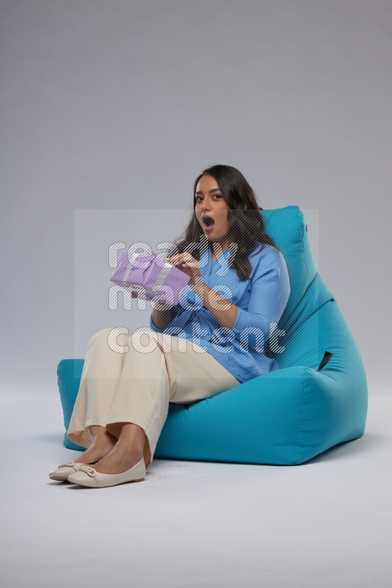 A woman sitting on a blue beanbag and holding a gift