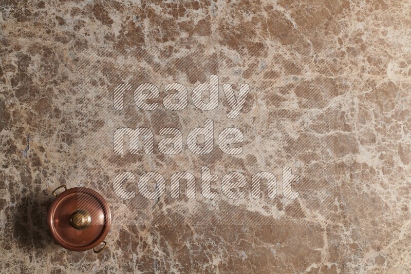 A small copper pot on beige marble background