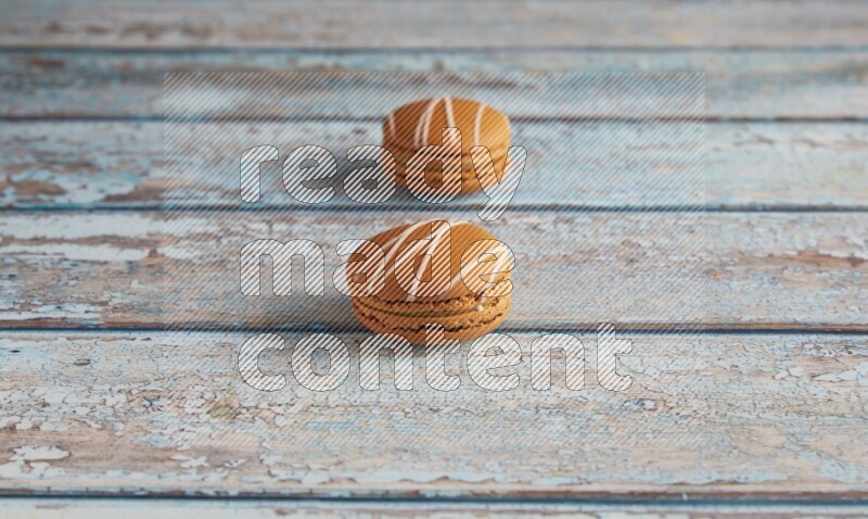 45º Shot of two Brown Irish Cream macarons on a  light blue wooden background