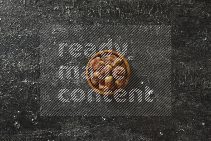 Dates in wooden bowls in a dark setup