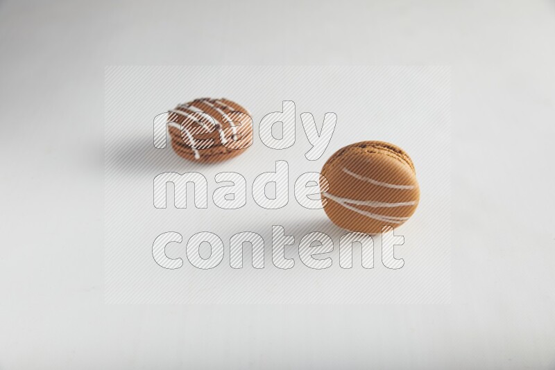 45º Shot of of two assorted Brown Irish Cream, and Brown white Chocolate Caramel macarons on white background
