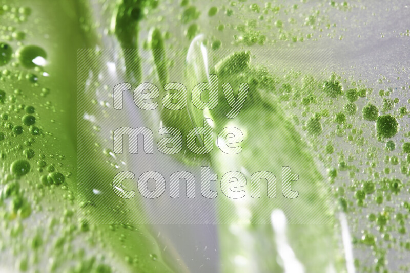 Close-ups of abstract green watercolor drops on oil Surface on white background