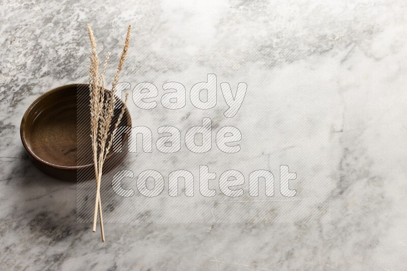 Wheat stalks on multicolored pottery oven plate on grey marble background