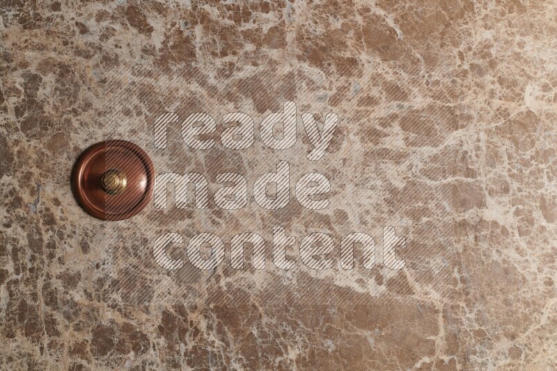A small copper pot on beige marble background