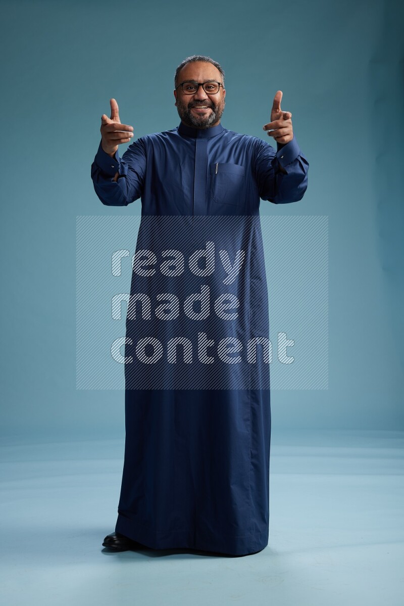 Saudi Man without shimag Standing Interacting with the camera on blue background
