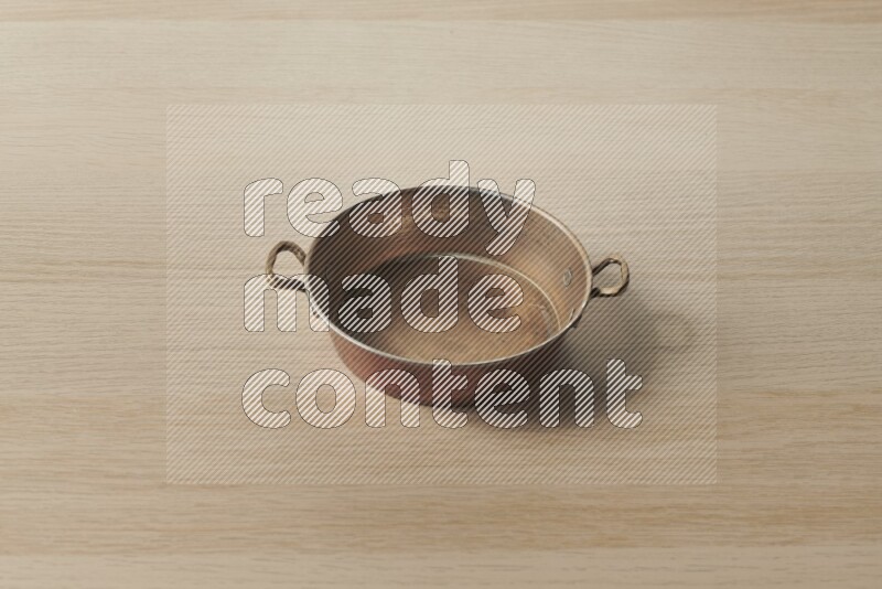 A small copper pan on light wooden background